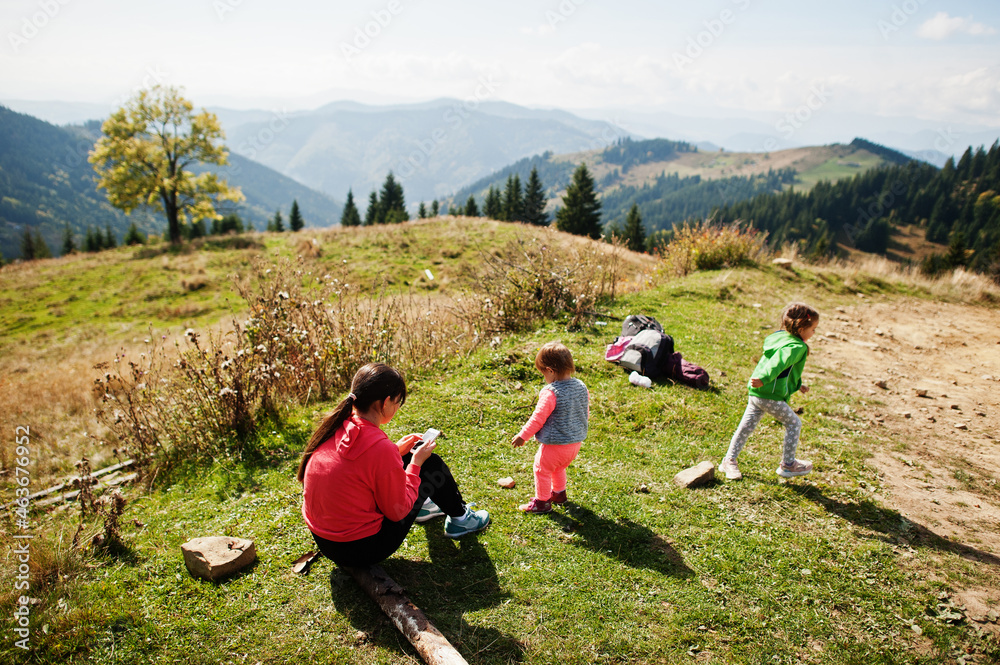 Fototapeta premium Mother with daughters enjoying in the mountains.The concept of family travel, adventure, and tourism. Lifestyle and hiking autumn vacations outdoor.