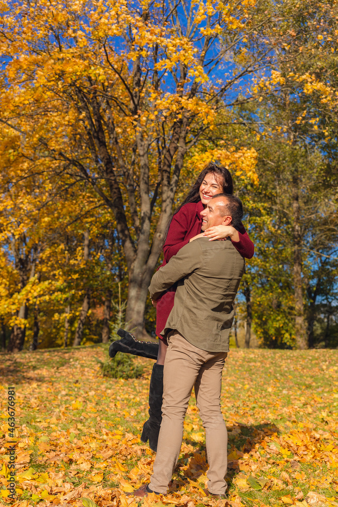 Lovely couple having fun together in nature. Boyfriend carrying his girlfriend in his arms.