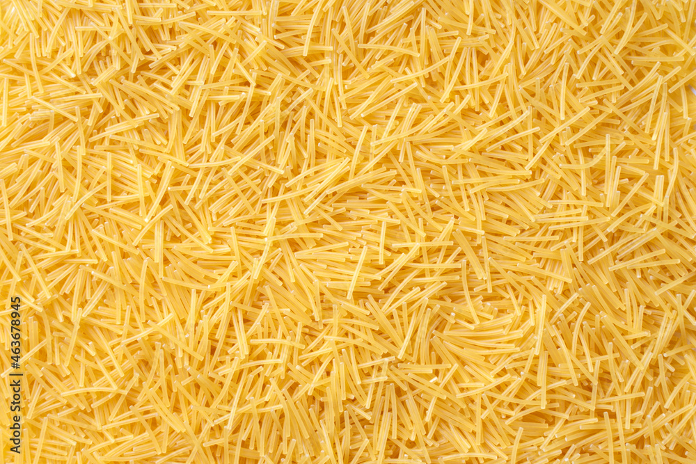 Obraz premium Delicious noodles texture. Healthy food and eating concept. Textured background with yellow pasta. Macaroni for soup. Uncooked Italian vermicelli. High-quality photo closeup