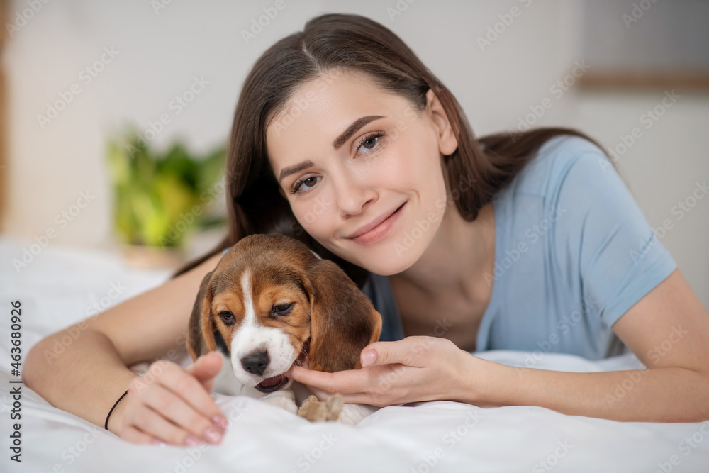 A pet owner sitting on bed and felling happy with her pet A pet owner sitting on bed and felling happy with her pet