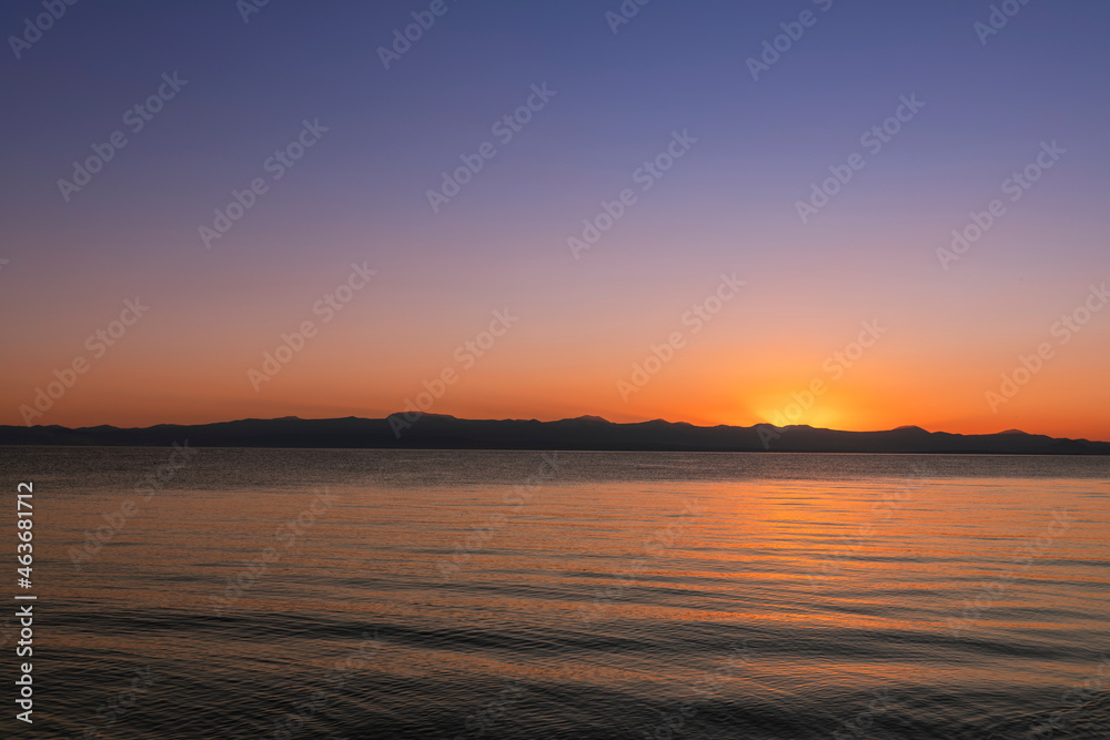 
Beautiful bright sunset sky on the lake and silhouette mountains on the horizon.