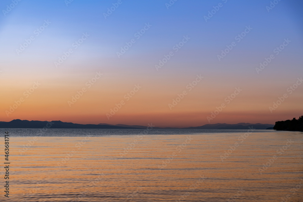 
Beautiful bright sunset sky on the lake and silhouette mountains on the horizon.