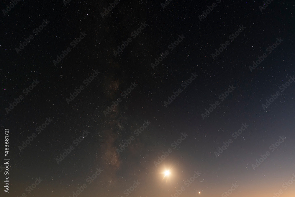 Beautiful bright milky way galaxy with long exposure cloud on the blue starry sky  and moon. Space, astronomical background. Cosmos wallpaper.