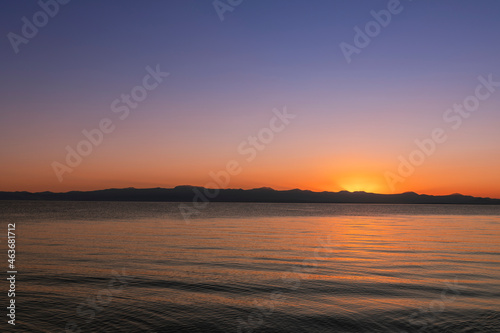  Beautiful bright sunset sky on the lake and silhouette mountains on the horizon.
