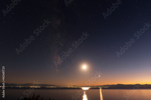 Night landscape, milky way galaxy and moon above the lake.