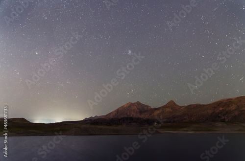 Beautiful night landscape. Small lake and mountains under starry sky.