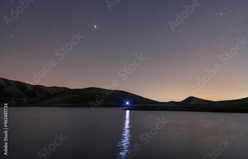 Beautiful night landscape. Small lake and mountains under starry sky.