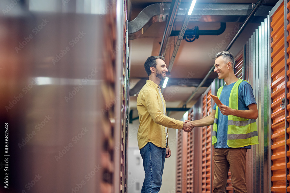 Two men shaking hands near warehouse garages
