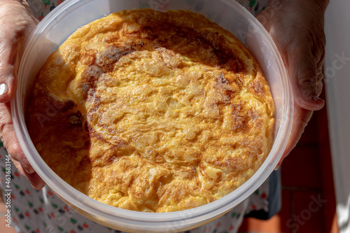 Spanish omelette in a plastic container, held by a woman's hands