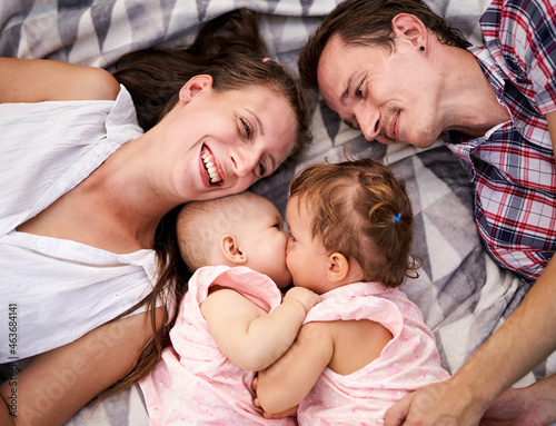 Happy family lies on a picnic blanket together - Young parents with a toddler and a baby daughter having fun - Bonding, love and care lifestyle concept from top view