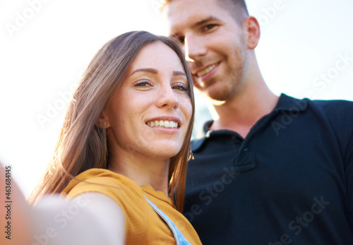 Happy millenial couple taking selfie outdoors