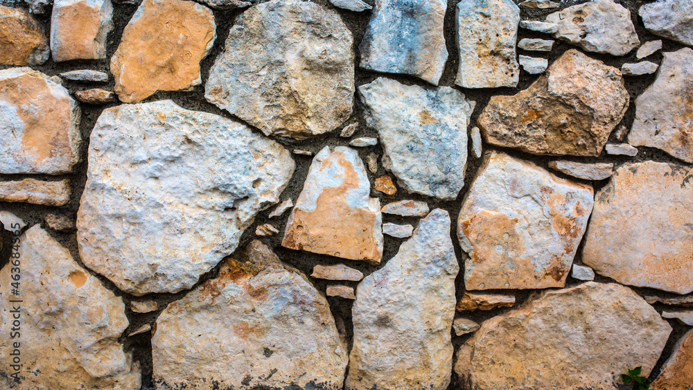 Stone antique old wall as a background or texture. Vintage background of a fortress wall in loft and grunge style with place for text and copy space.