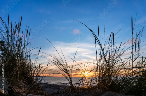 Sunset over the sea. Reflection of sunlight in the sea waves. Red and yellow sky in the rays of the sunset.