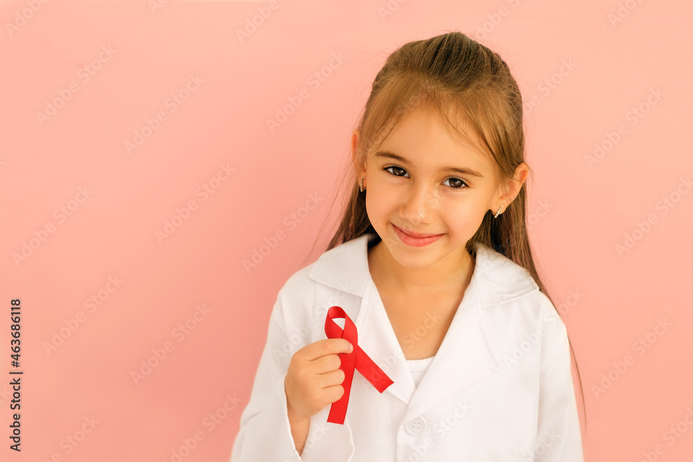 World awareness AIDS Day. A smiling child with a red ribbon loop in hand is a symbol of HIV awareness, hope for a cure, protection from discrimination. A girl in a white doctor's coat. pink background World awareness AIDS Day. A smiling child with a red ribbon loop in hand is a symbol of HIV awareness, hope for a cure, protection from discrimination. A girl in a white doctor's coat. pink background