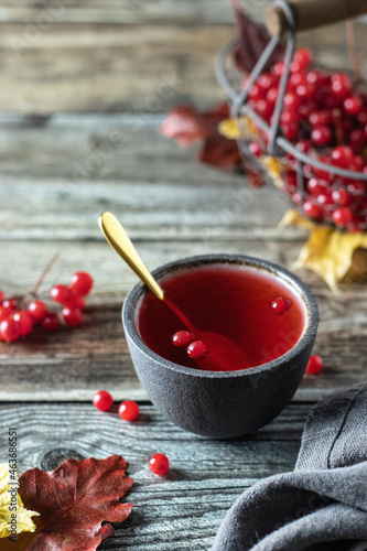 Tea with viburnum berries in a bowl, on a wooden table