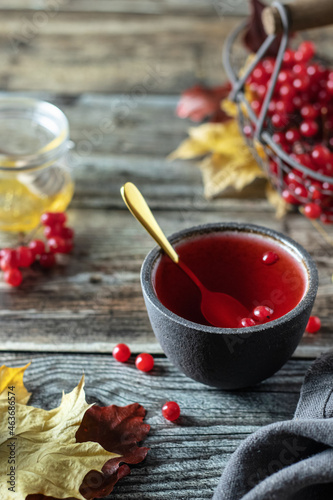 Tea with viburnum berries in a bowl, on a wooden table