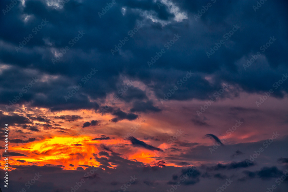 Epic orange fire sky with multicolored iconic dark clouds of yellow, orange on dramatic background.