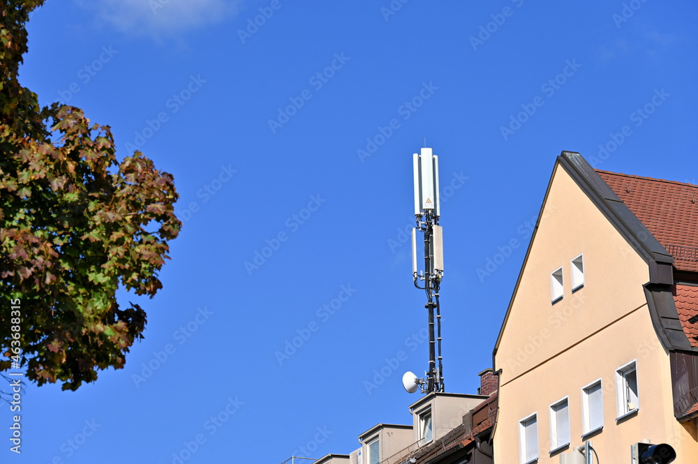 Mobilfunkantenne auf Hausdach vor blauem Himmel 