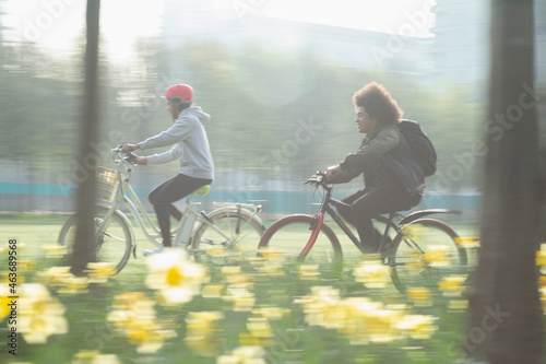 Teen friends riding bicycles in sunny spring park photo