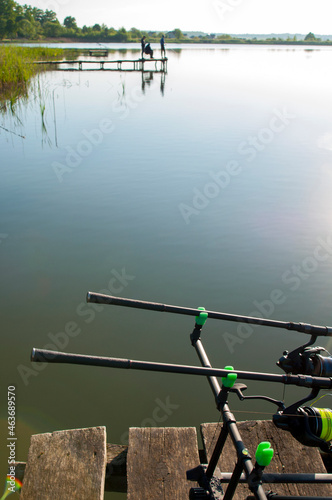 fisherman with fishing rods at sunrise on the lake