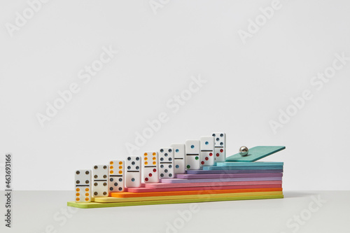Metal sphere rolling on colored dominoes photo