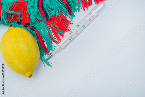 A warm winter scarf, thermometer, lemon lie on the side on a white background with a place for text. High quality photo photo