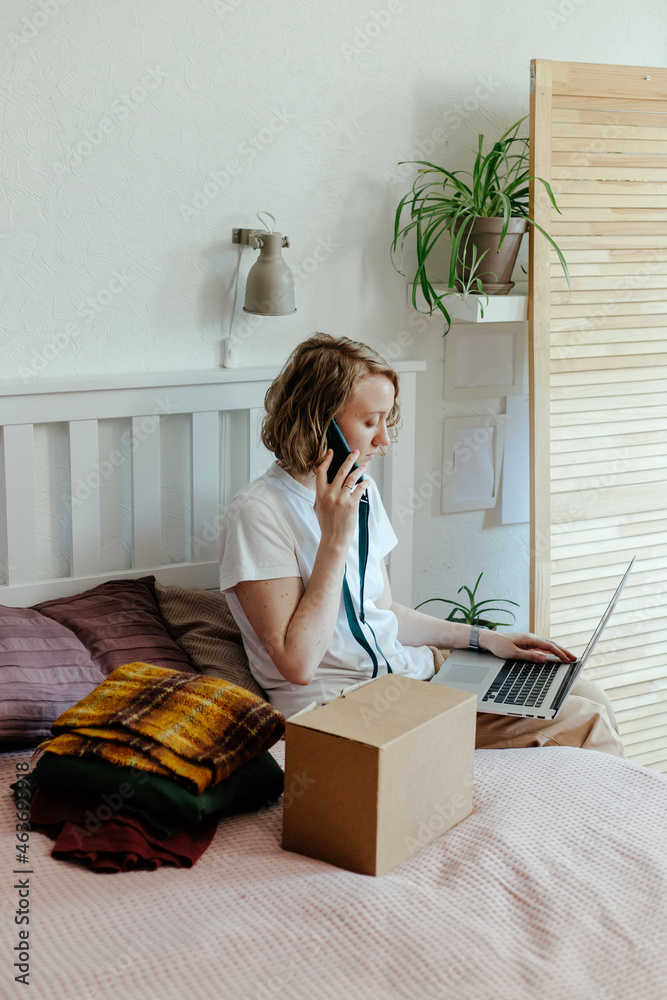 © Sergey Narevskih/Stocksy - Woman with gadgets getting rid of clothes
