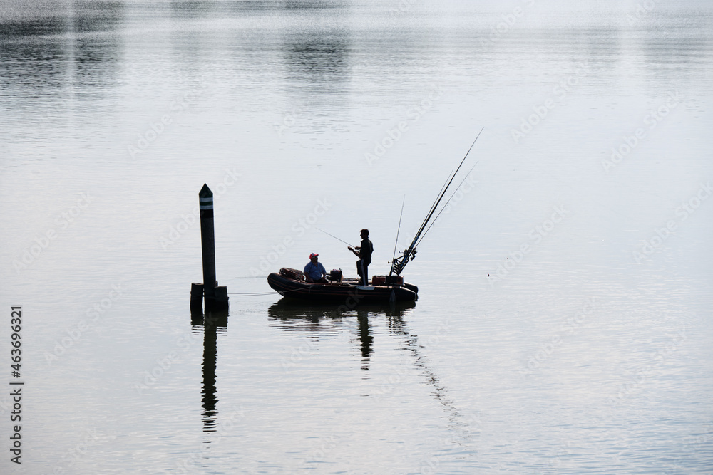 Silhouette of fishing rubber dinghy and fishermen