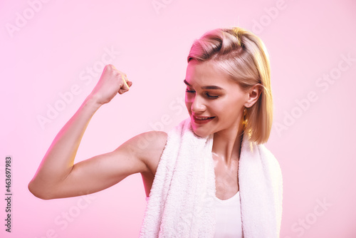 You are stronger than you think Attractive young sporty woman showing her bicep and smiling while standing against pink background