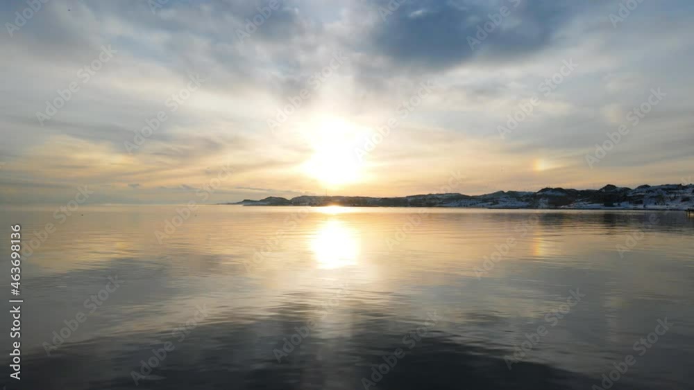 Wonderful frozen cold winter lake in sunset background. Aerial cinematic drone clip of frozen river, snowy coastline and cloudy skyline.