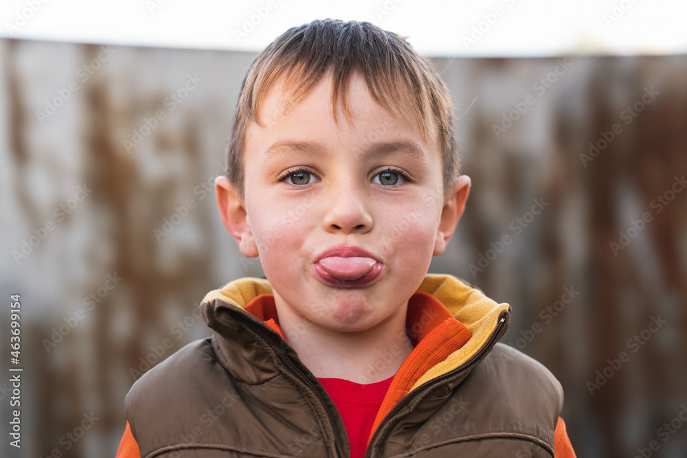 Close-up of a boy in a brown autumn vest showing his tongue. Close-up of a boy in a brown autumn vest showing his tongue.