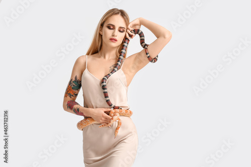 Sexy young woman with snakes on light background