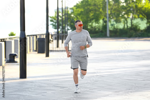Sporty mature man in sunglasses running outdoors