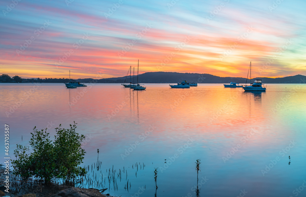 Sunrise waterscape with boats, reflections and high cloud