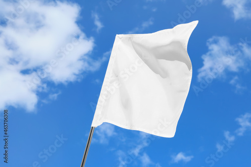 Waving white flag against blue sky