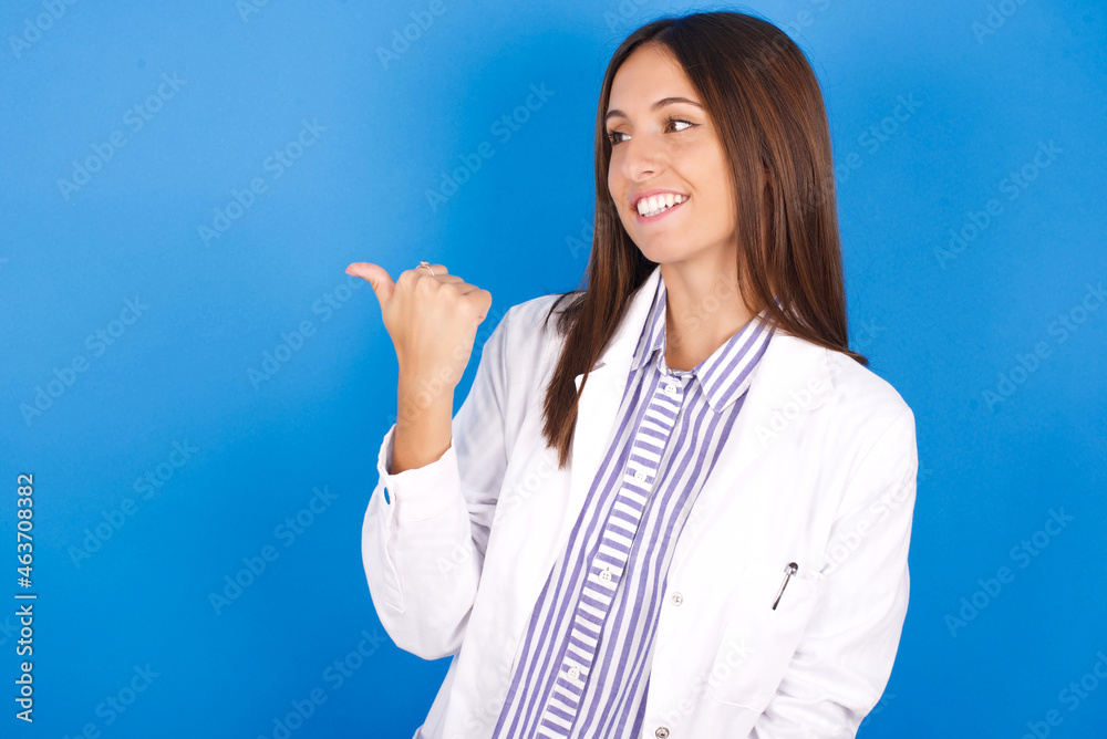 Charming Young european doctor woman on blue background looking at copy space having advertisements Charming Young european doctor woman on blue background looking at copy space having advertisements