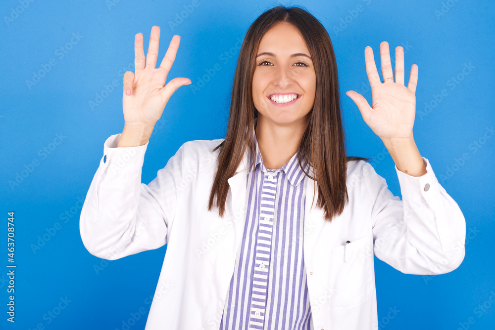 Young european doctor woman on blue background showing and pointing up with fingers number nine while smiling confident and happy. Young european doctor woman on blue background showing and pointing up with fingers number nine while smiling confident and happy.