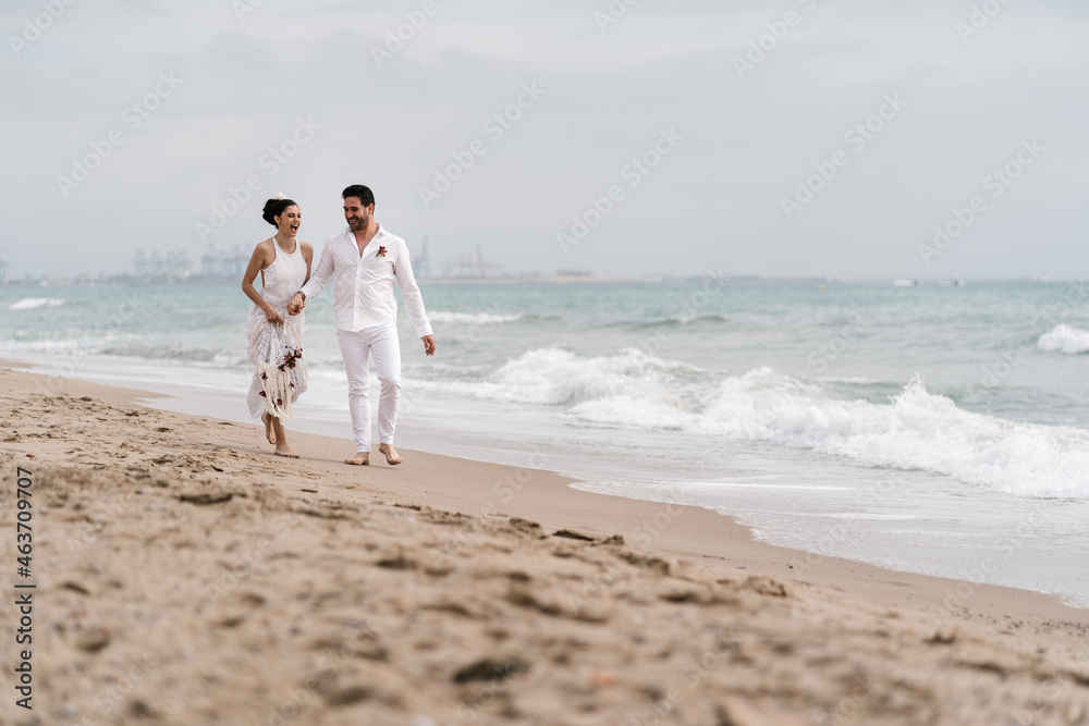 Happy newlyweds walking on the beach Happy newlyweds walking on the beach