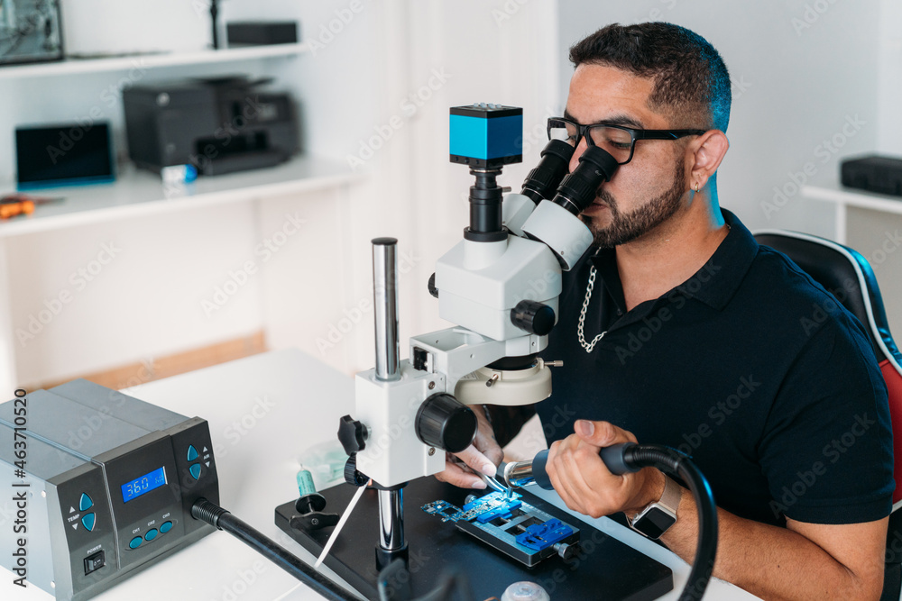 Male worker removing microchip with precision Male worker removing microchip with precision