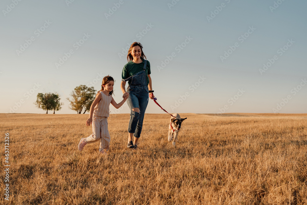 Mother and daughter hand in hand with a dog at field Mother and daughter hand in hand with a dog at field