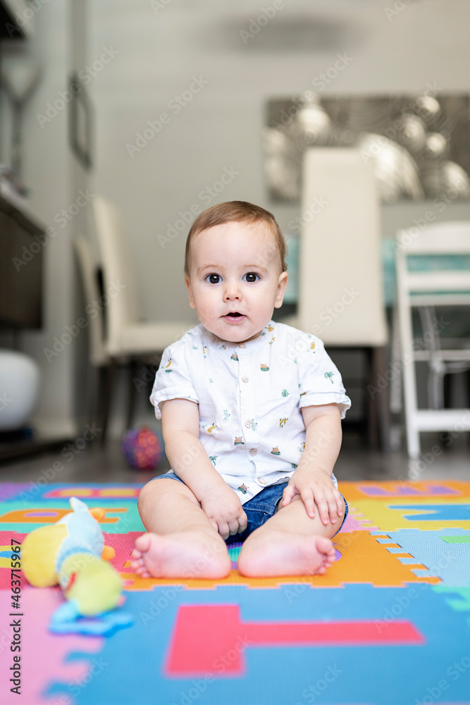 Portrait of baby boy sitting on floor in playroom with shirt Portrait of baby boy sitting on floor in playroom with shirt