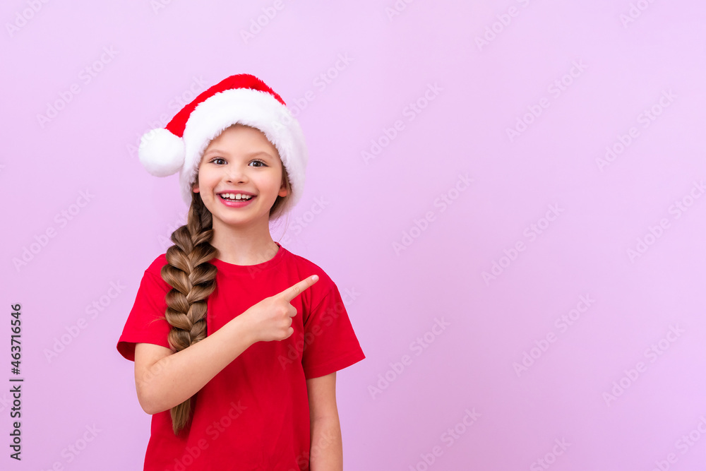 A little girl in a New Year's hat and a red T-shirt points her finger at the advertisement. A little girl in a New Year's hat and a red T-shirt points her finger at the advertisement.