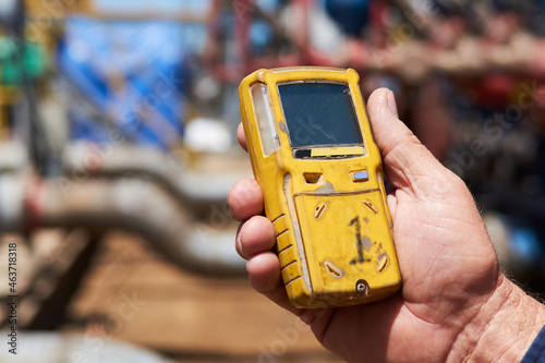 Worker at gas drilling site hoarding gas detection monitor photo
