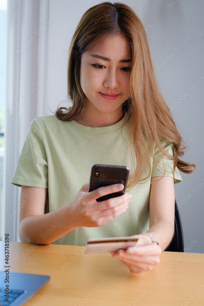 Woman enjoy with online shopping application on cell phone and use camera to scan credit card for fill number to payment Woman enjoy with online shopping application on cell phone and use camera to scan credit card for fill number to payment