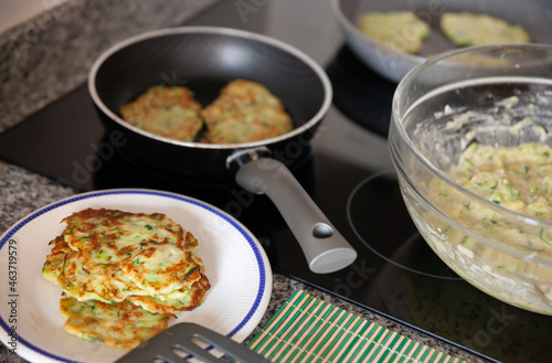 Plate with stack of hot fried homemade zucchini fritters on kitchen table © JackF