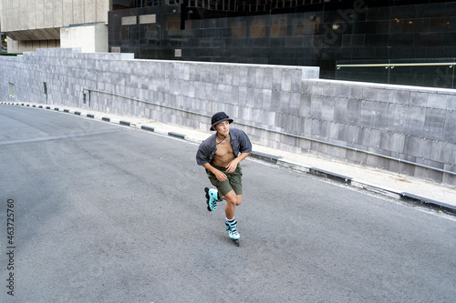 Young male roller skating in the asphalt with a concrete wall background