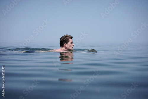 Sportive young male swimming in the blue sea in sumemr photo