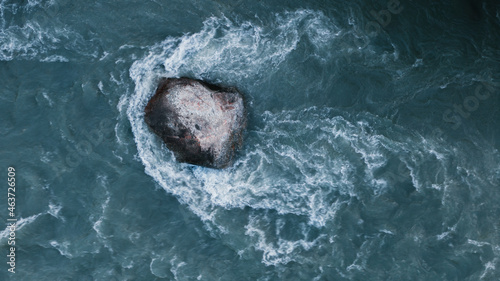 large stone rock in the middle of a river flow