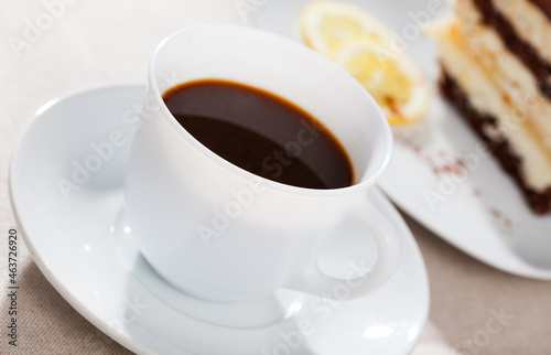 Cup of coffee served with slice of delicious chocolate lemon cake