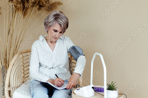 Elderly woman measuring blood pressure photo